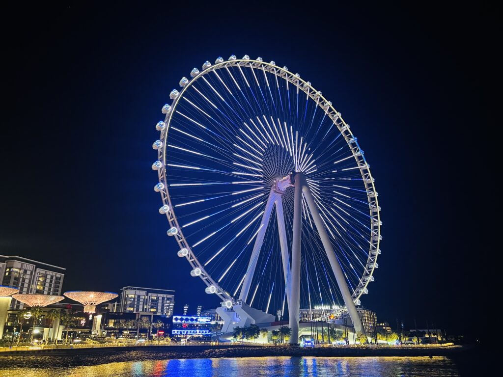 A stunning night view of the big wheel in Dubai, illuminating the cityscape with its vibrant lights.